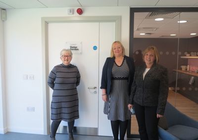 Photograph of Glenys, our founder, alongside two members of staff from Slater & Gordon Lawyers. They are standing in front of Glenys' new room which has a Slater & Gordon plaque on the door. 